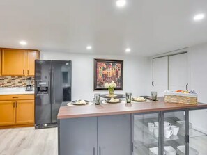 Een moderne keuken met een centraal eiland, roestvrijstalen apparatuur en een groot stadsgezicht in een lijst.