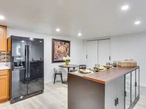 Een moderne keuken met een grote koelkast, een eettafel met stoelen en een keukeneiland.