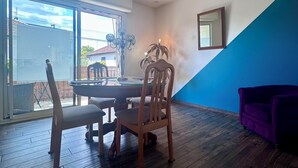 Un coin repas avec une table et des chaises en bois, un lustre et une vue à travers une porte-fenêtre coulissante.