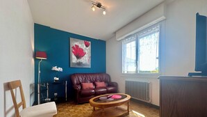 Un salon avec un mur bleu, un canapé en cuir marron, une table basse en bois et une fenêtre avec des stores.