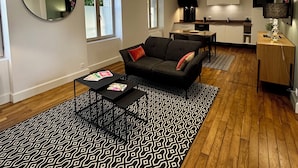 Una sala de estar moderna con un sofá negro, una mesa de centro y un tapete estampado.