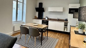 Una cocina moderna con comedor, que cuenta con un amplio ventanal, una campana extractora negra y un horno empotrado.