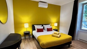 Ein modernes Hotelzimmer mit einem großen Bett, zwei Nachttischen, einem Schreibtisch und einem Fenster mit Vorhängen.