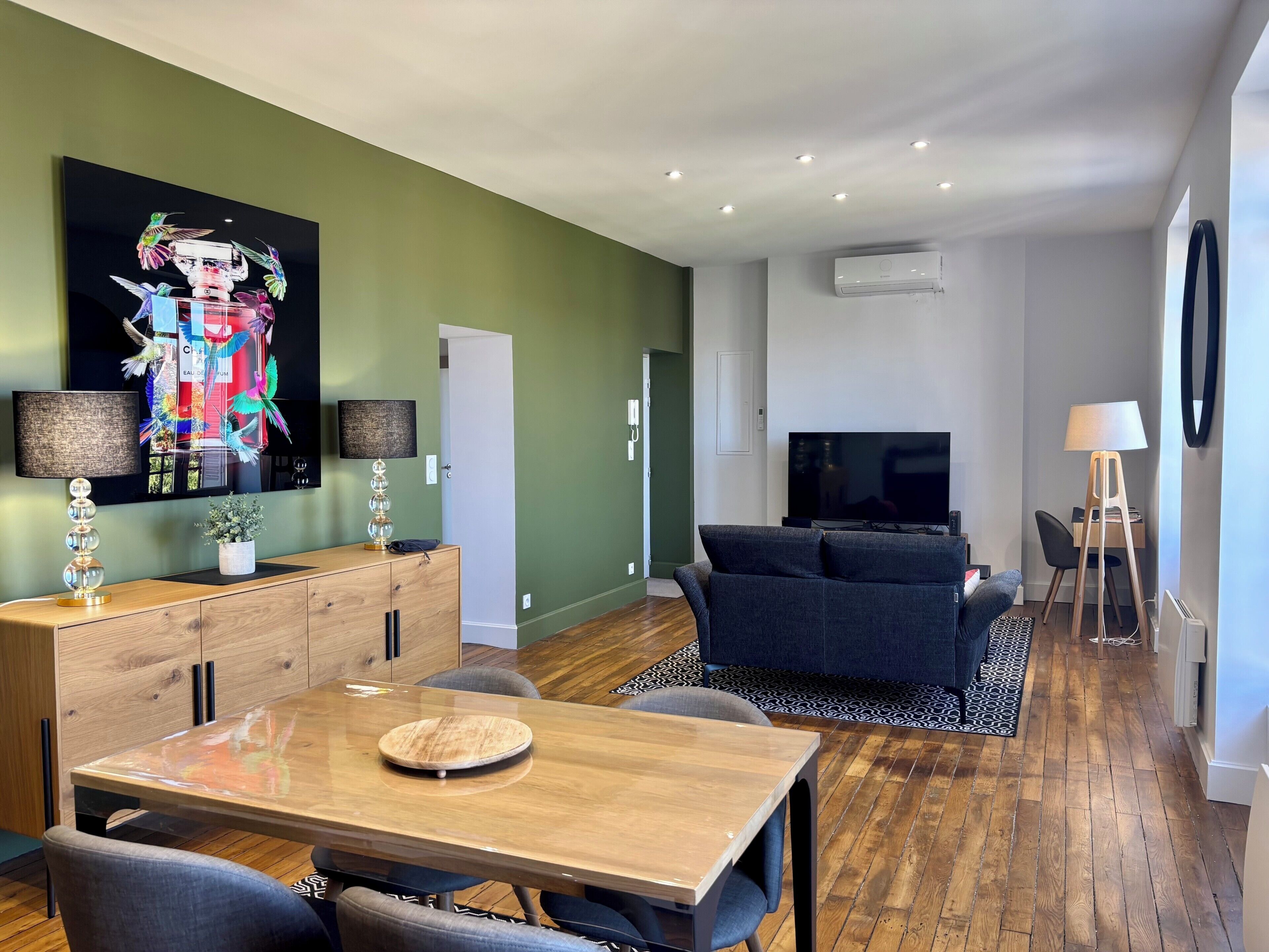 Ett modernt vardagsrum med en soffa, en tv och en matplats med ett bord och stolar.