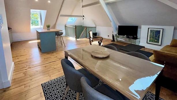A spacious loft apartment with a high ceiling, a dining area, a kitchen, and a living room.