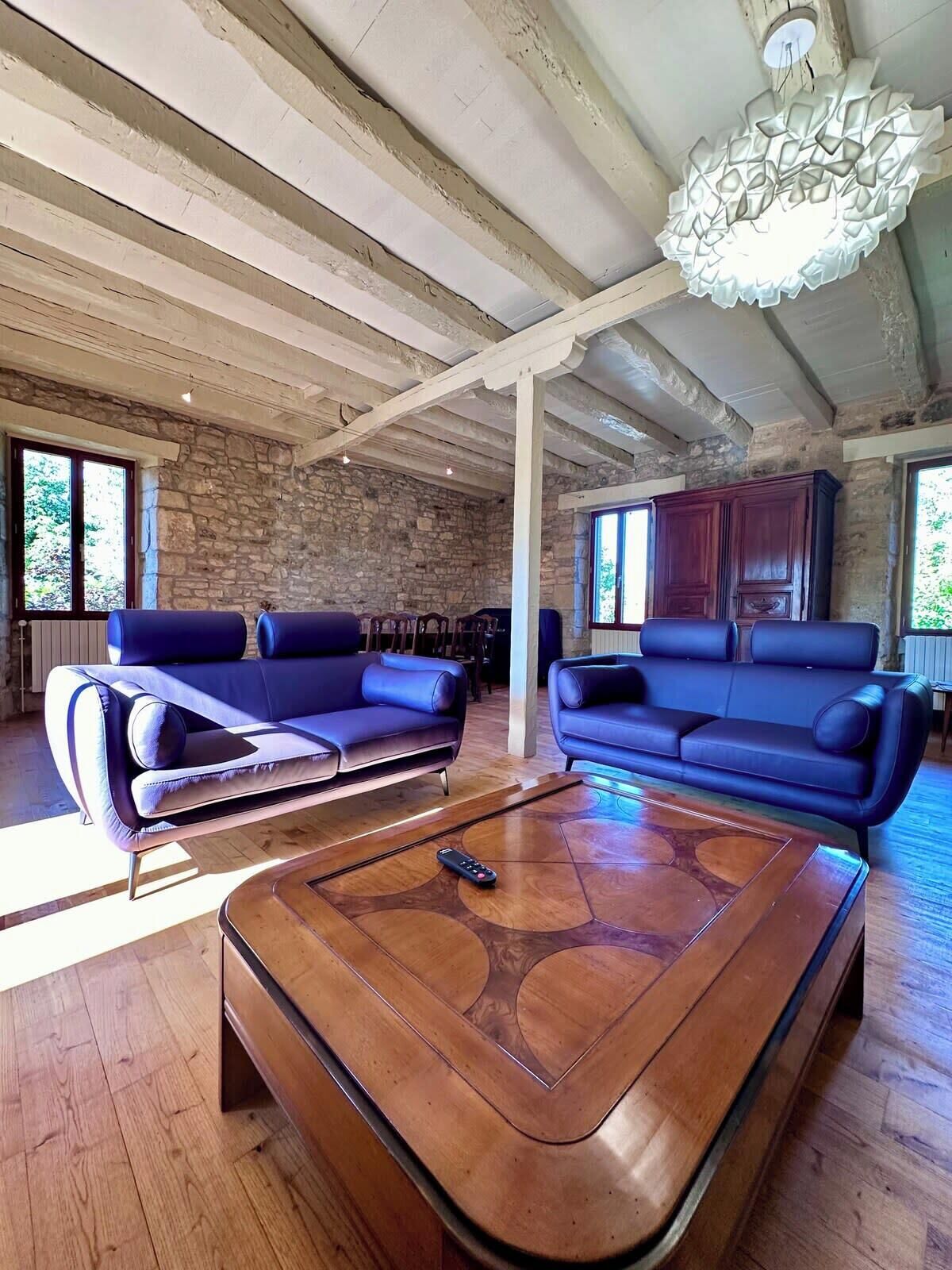 Un salon spacieux avec deux canapés bleus, une table basse en bois et un mur en pierre.