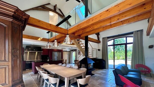 A spacious living area with a wooden dining table, modern chairs, a fireplace, and a view of the outdoors.