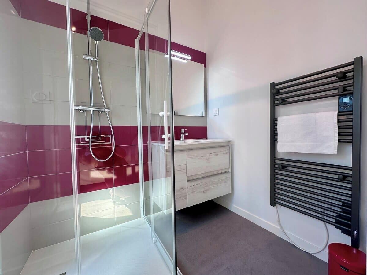 Un bagno moderno con cabina doccia in vetro, un mobile vanitario con specchio e un porta asciugamani.