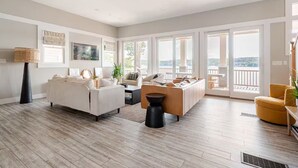 Un salón espacioso con un sofá grande, una mesa de centro y un sillón amarillo. Se aprecia una ventana amplia con vistas al exterior.