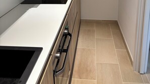 Een moderne keuken met een ingebouwde kookplaat, houten kastjes en een betegelde vloer.