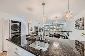 Una cocina moderna con una isla central, electrodomésticos de acero inoxidable e iluminación colgante.