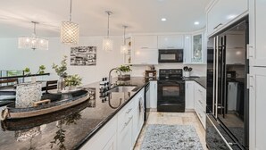 Una cucina moderna con mobili bianchi, un piano di lavoro nero e un forno integrato.