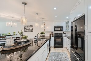 Una cocina moderna con gabinetes blancos, encimera negra y horno integrado.