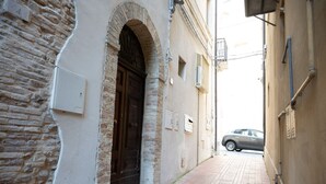 A narrow alleyway with a stone building on the left and a beige building on the right. There is a car parked at the end of the alley. - A Casa di Marilù - Lanciano (Lanciano)