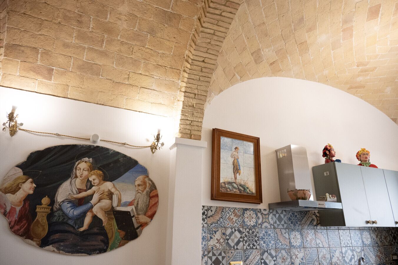 Una habitación con un mural, paredes con azulejos y un mueble con objetos decorativos.