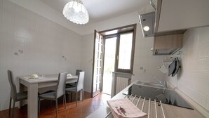 Uma cozinha compacta com área de refeições, uma janela e um porta-toalhas suspenso.