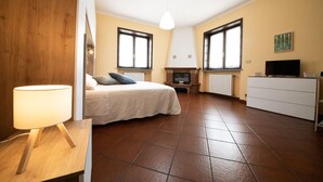 Quarto com cama, televisão, lareira e cômoda.