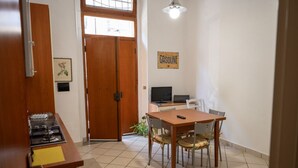 Eine kompakte Küche mit Gaskochfeld, einem Esstisch mit Stühlen, einem Fernseher und einer Tür mit Fenster.