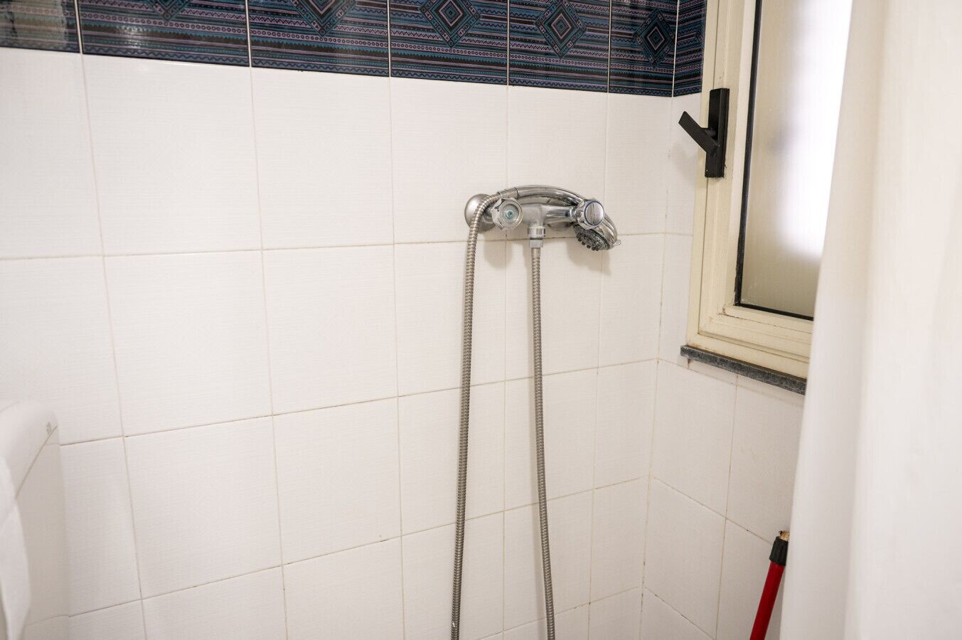 Une douche équipée d’un pommeau de douche à main et d’un robinet fixé au mur.