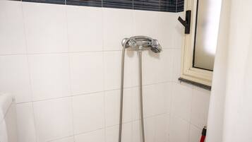 Une douche équipée d’un pommeau de douche à main et d’un robinet fixé au mur.