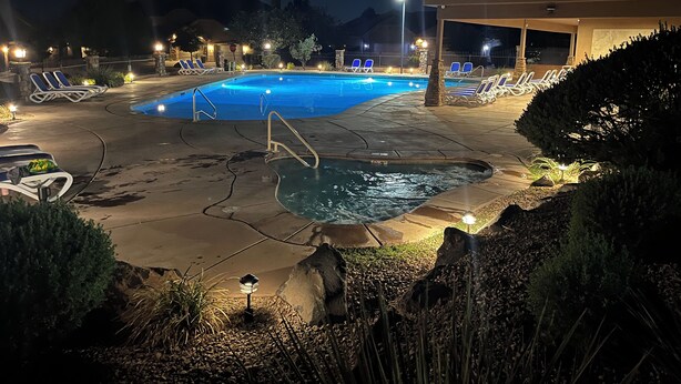 A swimming pool area with lounge chairs and a hot tub, surrounded by well-lit pathways and vegetation. - 100% of REVIEWS ARE 5 STARS!! GORGEOUS TOWNHOME with 5 TVs, popcorn machine, BBQ (Washington)