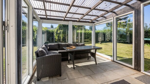 Un área de patio techada con un sofá, una mesa y un tablero de ajedrez.