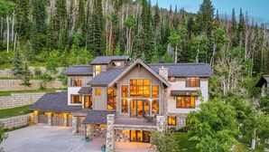 A large, multi-story house with a stone foundation, multiple windows, and a well-maintained lawn.