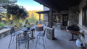 An outdoor patio with stone walls, a fire pit, and outdoor seating.