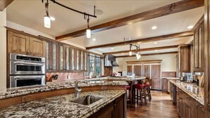 A spacious kitchen with granite countertops, stainless steel appliances, and wooden cabinetry.