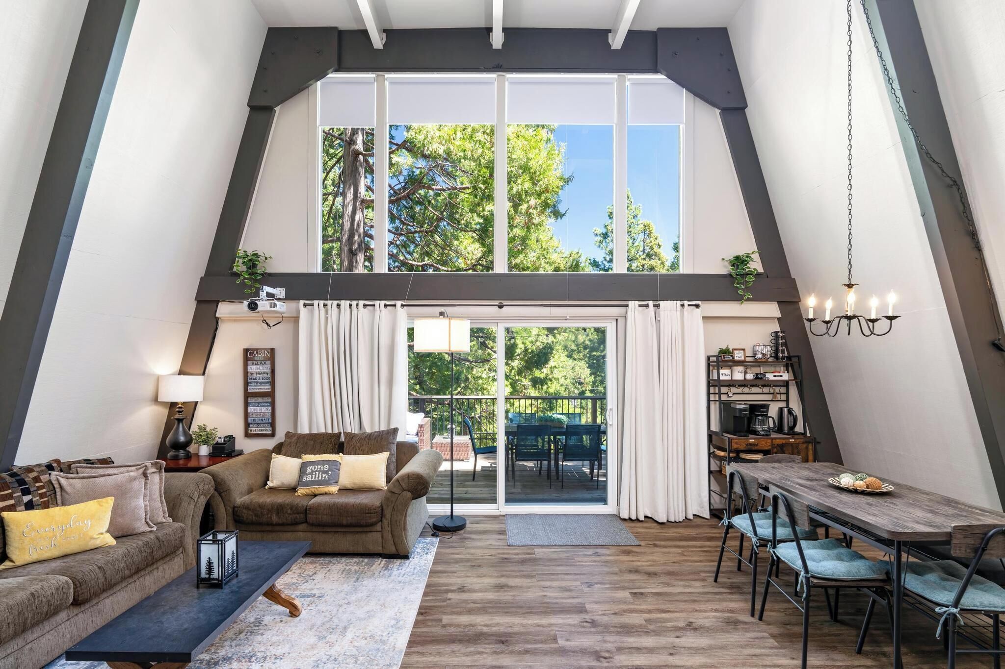 A spacious loft-style living area with a high ceiling, a dining table, and a sliding glass door leading to an outdoor patio.