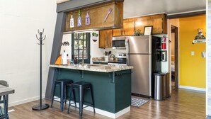 A modern kitchen with a central island, stainless steel appliances, and a yellow accent wall.