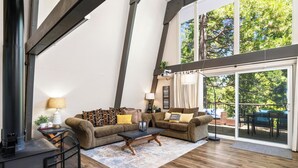 A spacious living room with a large window, a fireplace, and a balcony with outdoor furniture.