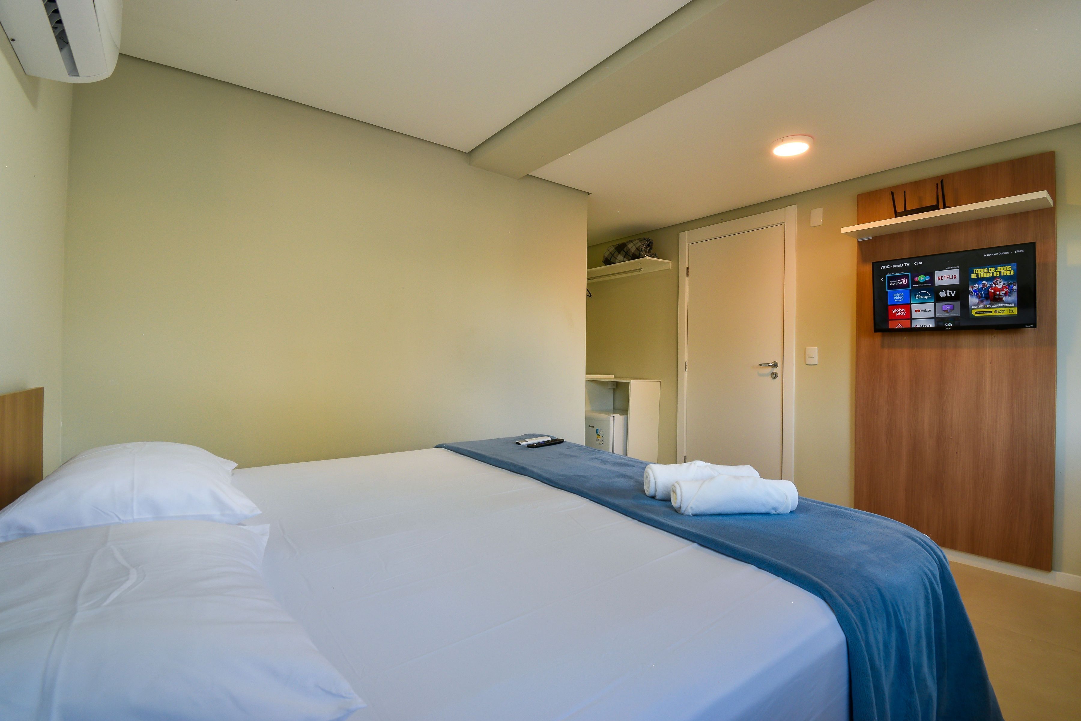 A hotel room with a bed, a TV mounted on the wall, and a door leading to a closet.