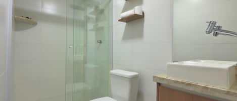 Un baño moderno con ducha envuelta en vidrio, inodoro y lavamanos con encimera de madera.