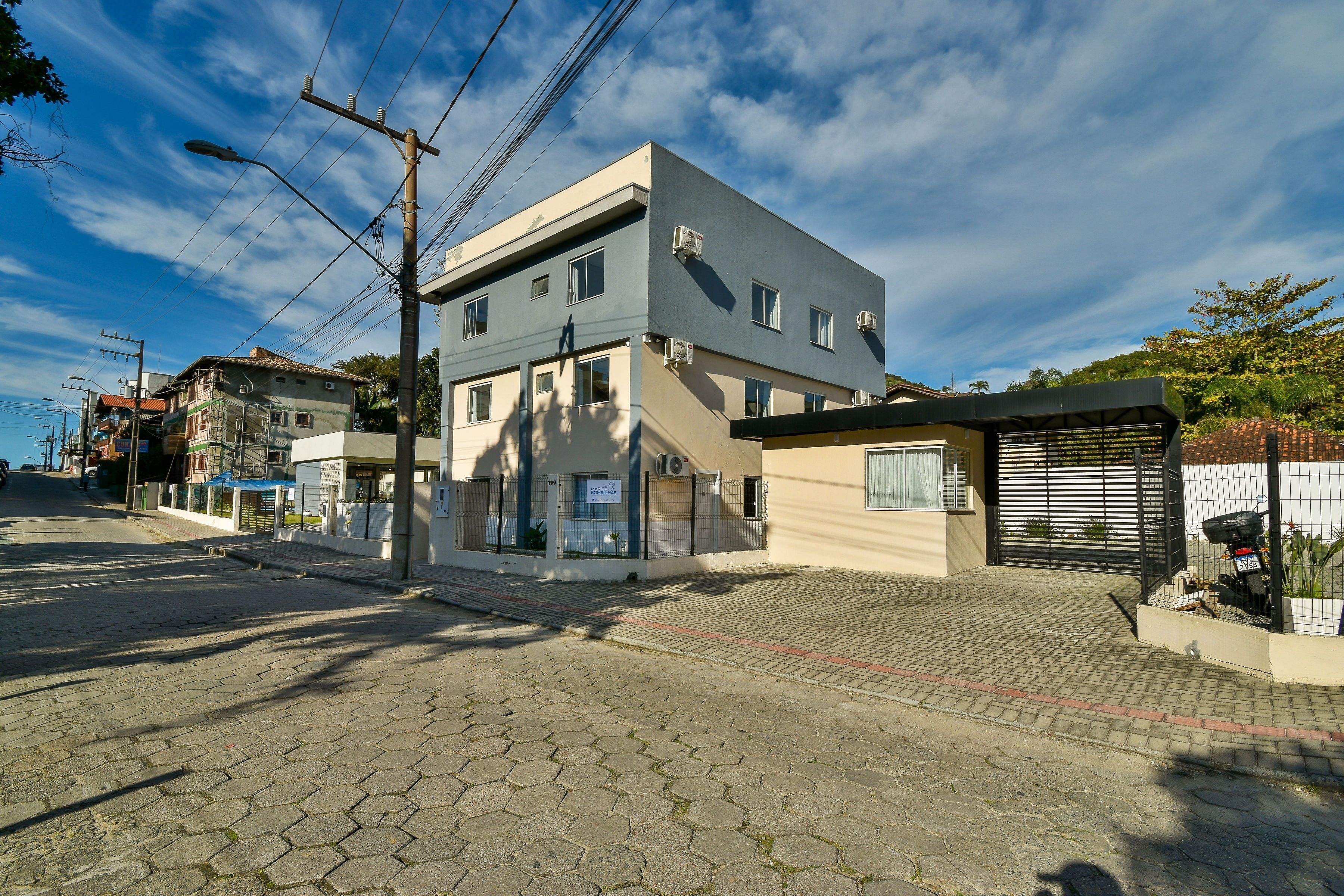 A modern building with a flat roof, multiple windows, and a paved entrance area.
