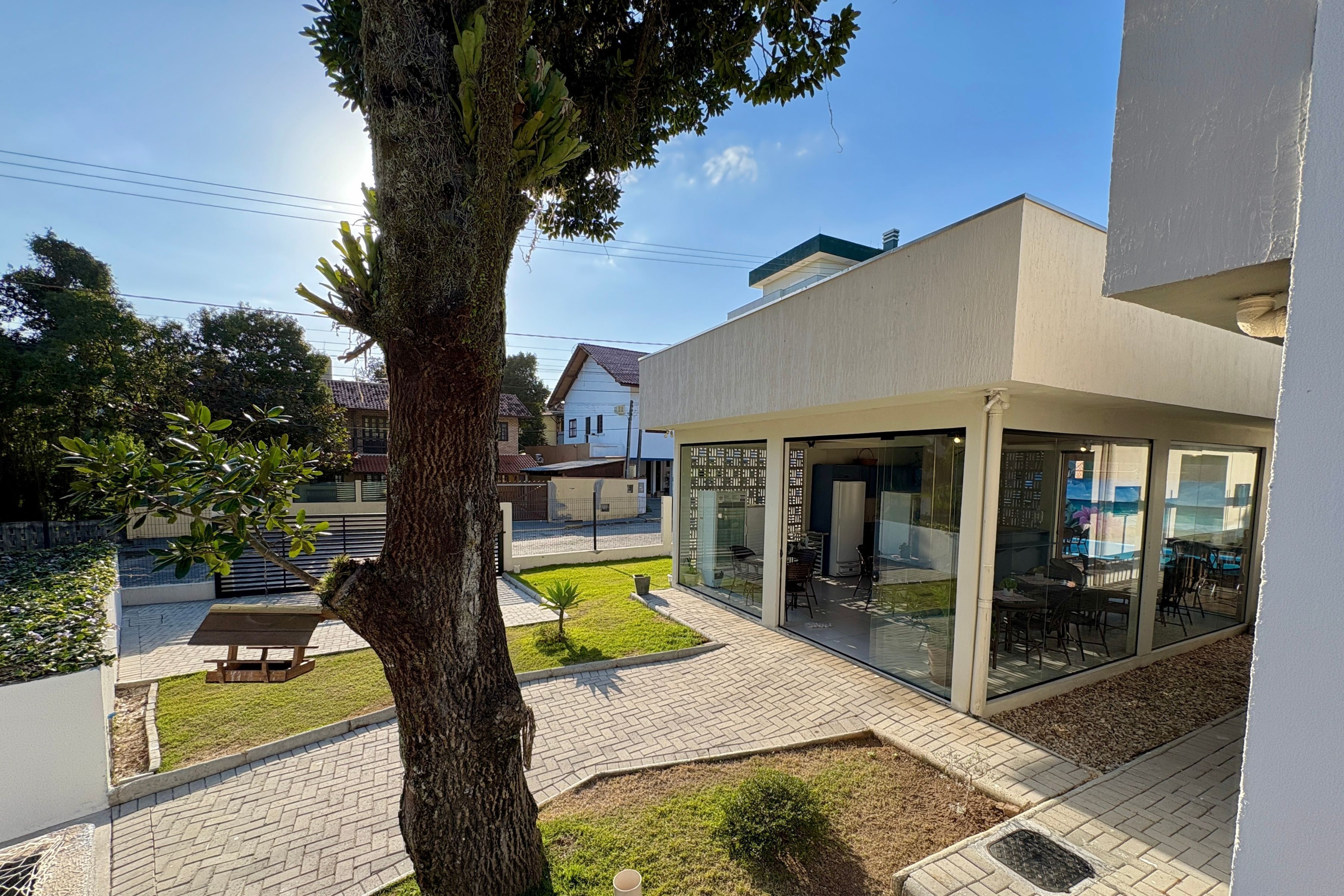 A modern building with a patio area, a tree, and a small lawn.
