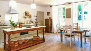 A kitchen with a wooden table, chairs, and a dining area with a view of the outdoors. - LARGETEAU astronomer's house (Mouilleron Saint Germa)