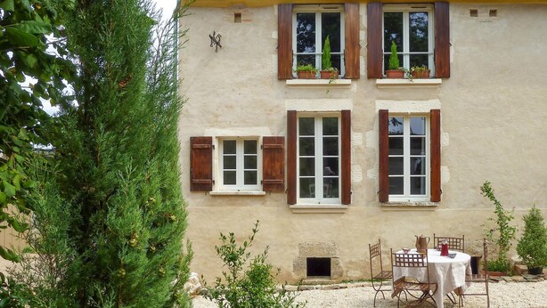 A building with multiple windows, some with shutters, and a table with chairs outside. - LARGETEAU astronomer's house (Mouilleron Saint Germa)