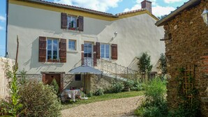 A two-story building with a balcony, a gravel driveway, and a garden area with a table and chairs. - LARGETEAU astronomer's house (Mouilleron Saint Germa)