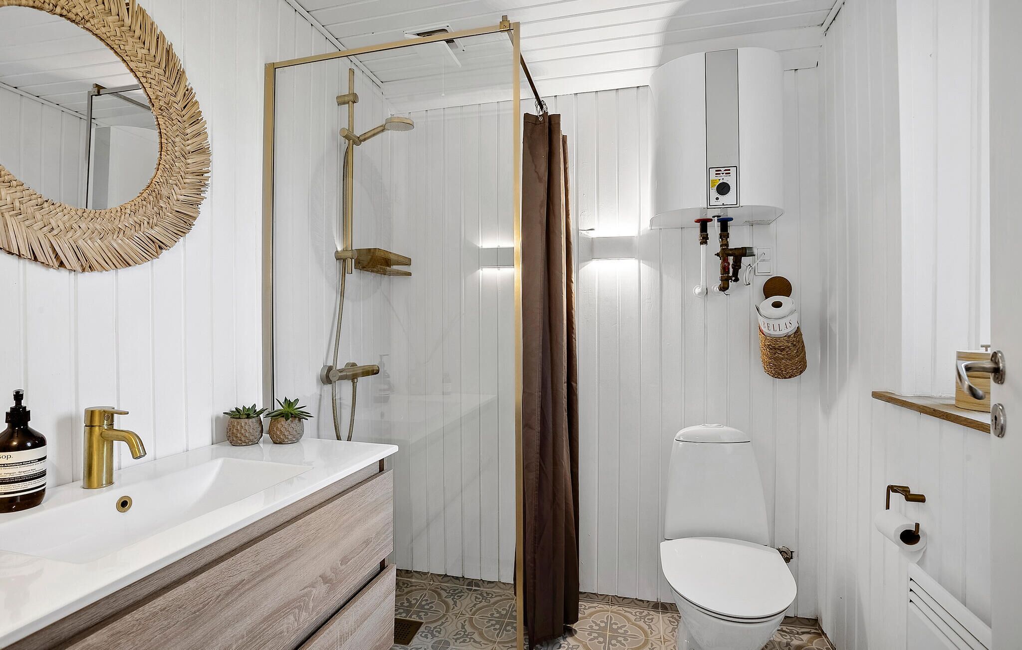 A bathroom with a white vanity, a gold faucet, a shower with a brown curtain, a toilet, and a wall-mounted towel rack.