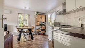 A modern kitchen with white cabinets, a wooden dining table, and a built-in bookshelf.