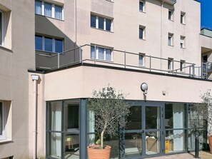 Een meerlaags gebouw met grote ramen, een balkon en een bloempot.