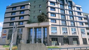 Un immeuble à plusieurs étages doté d’une architecture moderne, caractérisé par de grandes fenêtres et une façade texturée de couleur verte.