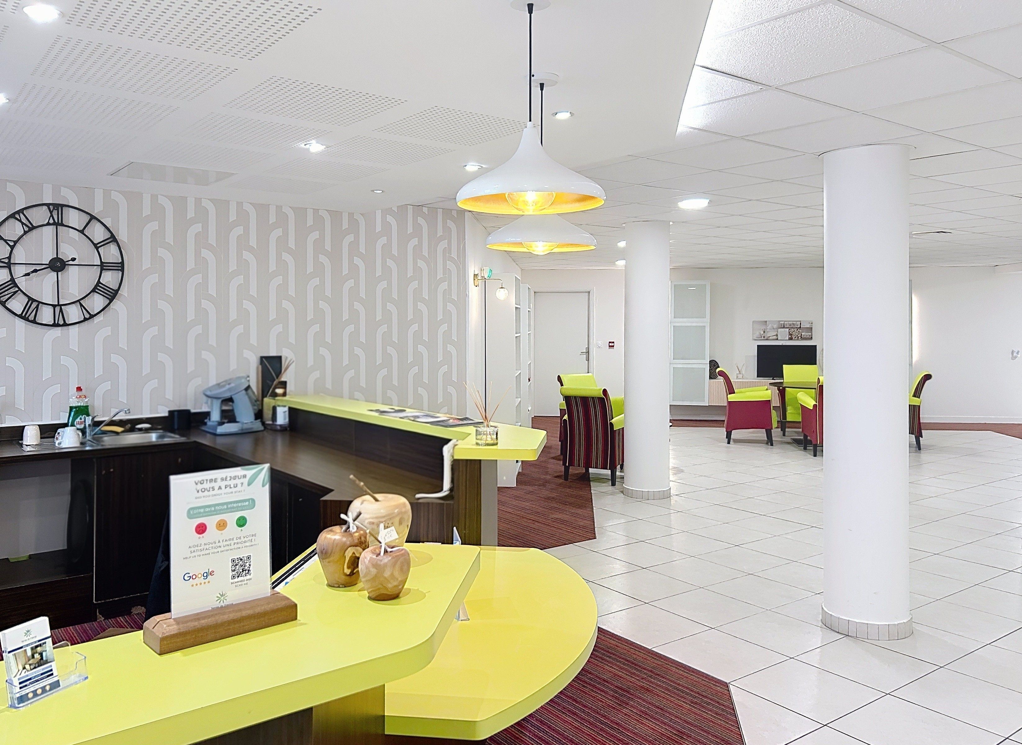 Un espace d’accueil d’hôtel comprenant une horloge, un comptoir de réception et des sièges.