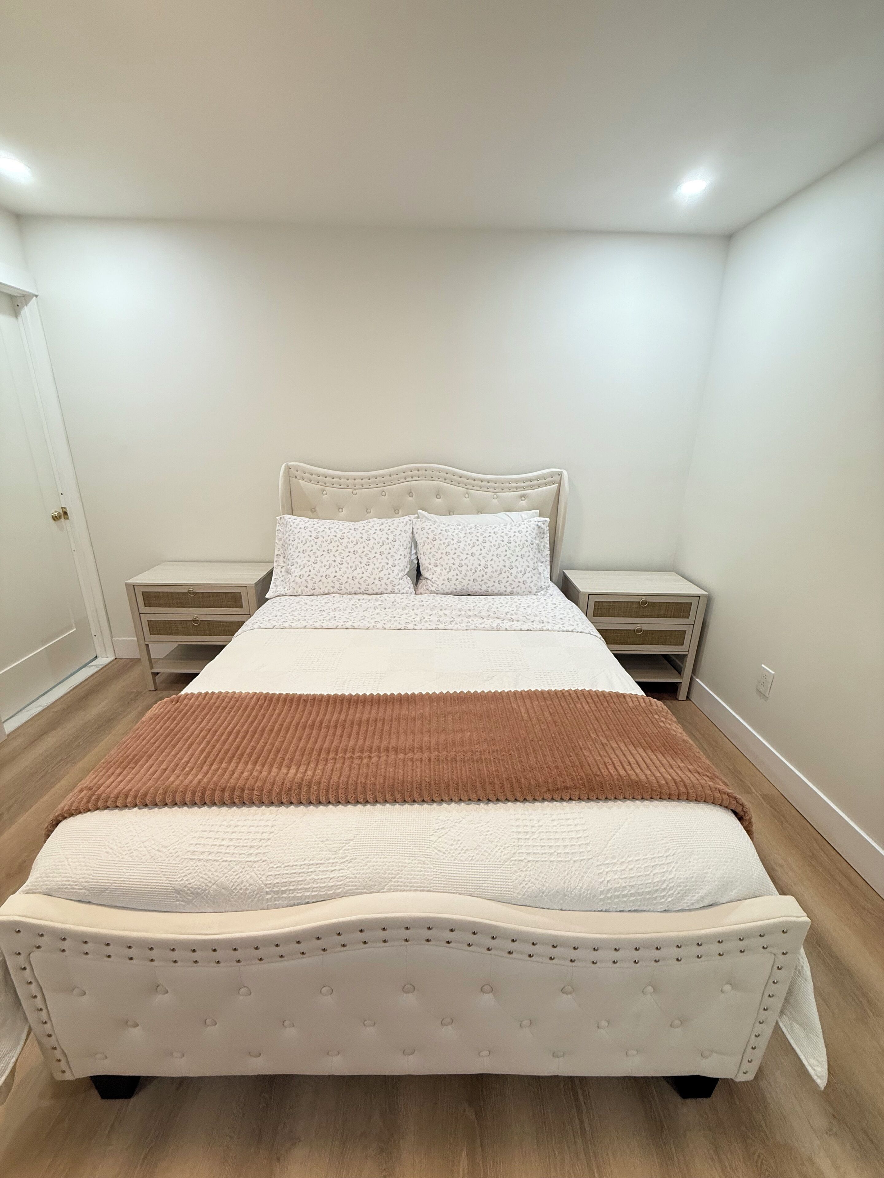 A neatly arranged bedroom with a bed, two bedside tables, and a door.