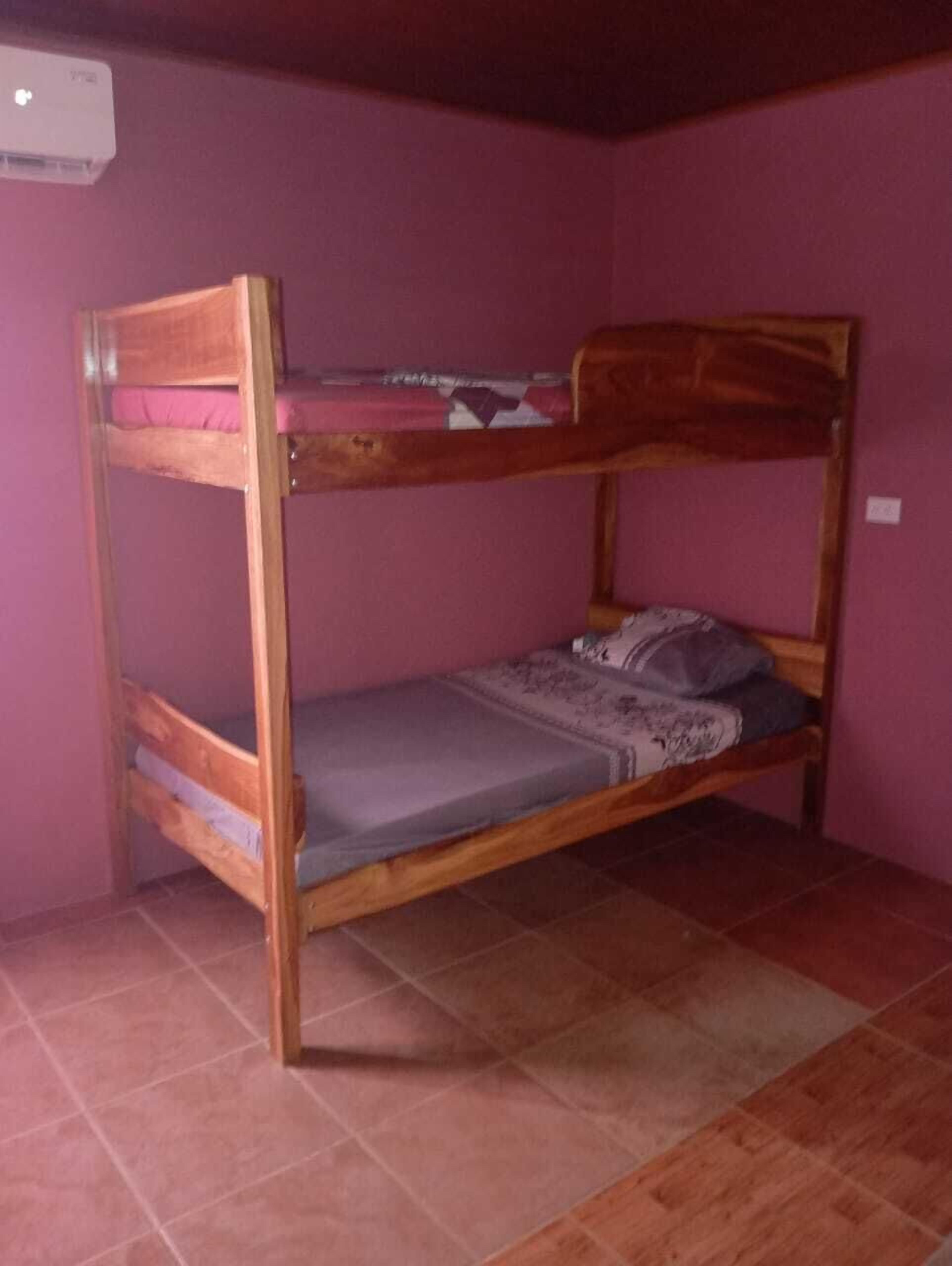 A bunk bed in a room with pink walls and tiled flooring.