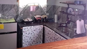 Una cocina compacta con salpicadero de mármol, encimera de madera y un lavabo.