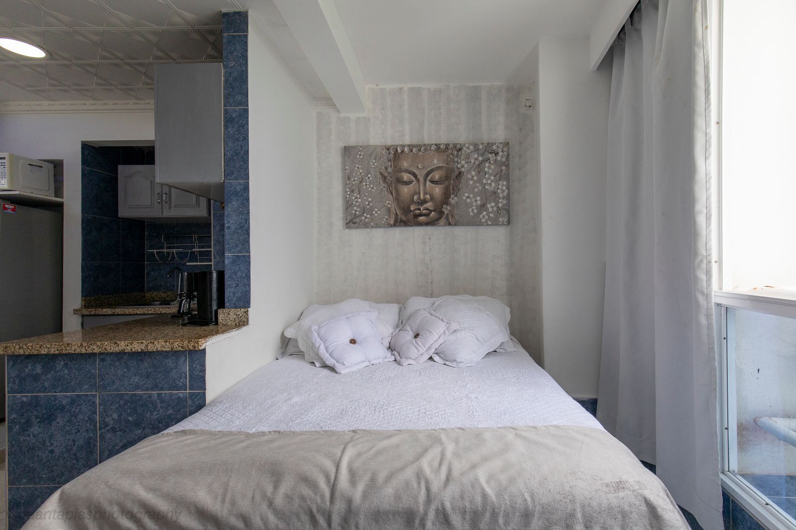 Une chambre à coucher avec un lit, une fenêtre et une œuvre d’art accrochée au mur.