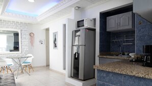 Una cocina moderna con microondas integrado, refrigerador de acero inoxidable y encimera de granito.