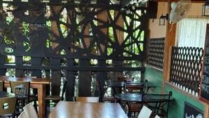 A long wooden table with chairs, surrounded by a lattice partition and a green wall with a sign. - Las Casitas italiana (Sabalito)